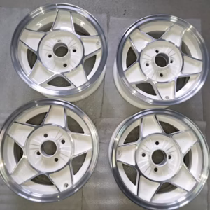 Ein Satz von vier ATS Classic Felgen Opel Manta Kadett 6x13 6036 mit silbernen Felgen ist paarweise auf einer grauen Fläche angeordnet.