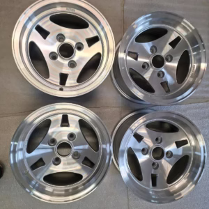 Vier Ats Ford Capri Escort Felgen 7x13 ET .5 KBA40469 Leichtmetallräder, jedes mit fünf Speichen, sind auf Beton dargestellt-zwei ruhen auf weißer Polsterung-perfekt für die Aufrüstung Ihres Ford Capri oder Escort.