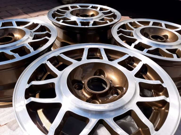 Vier Avus Snowflake Felgen Kiwi Braun Lp6v für Golf 1 und Scirocco mit bronzefarbenem und silbernem Finish werden im Sonnenlicht auf dem Boden präsentiert.