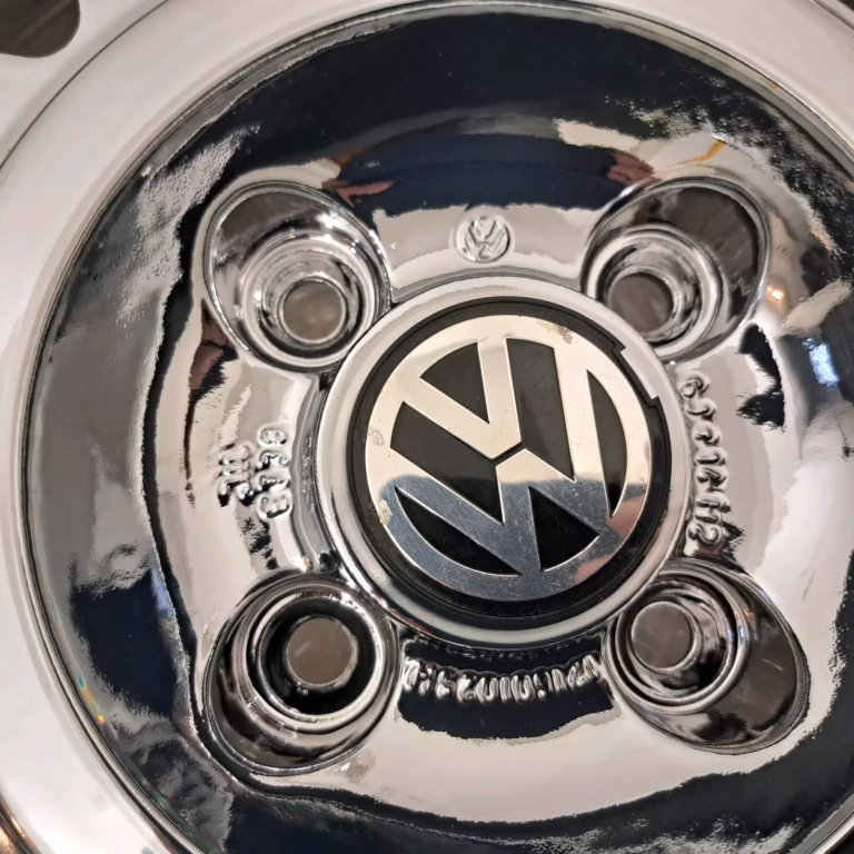 Nahaufnahme einer glänzenden Pvd Chrom Avus Snowflake Felgen Radkappe für Golf 1, Scirocco, oder Jetta, mit dem VW Logo in der Mitte und vier Schraubenlöchern.