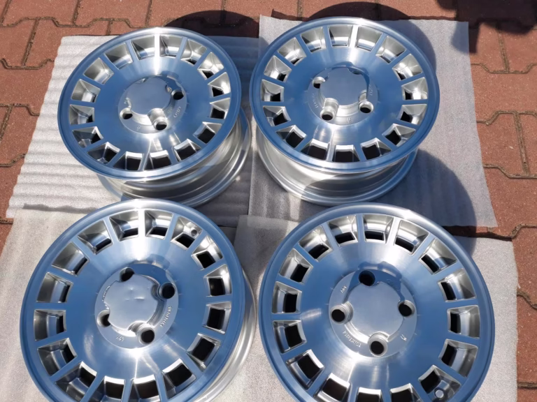 Vier Ford Capri Escort Fiesta Felgen Aufbereitet 5.5x13 mit geometrischen Speichen sind auf Outdoor-Schaumstoffmatten ausgestellt.