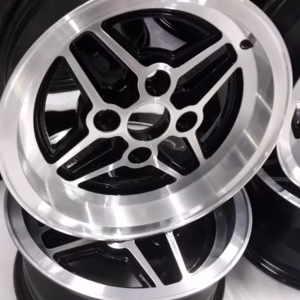 Nahaufnahme mehrerer glänzender schwarzer und silberner Ford Capri Rs Felgen Escort Fiesta Orion 6x13 Et19 Leichtmetallfelgen, die auf einer weißen Fläche aufeinander gestapelt sind.